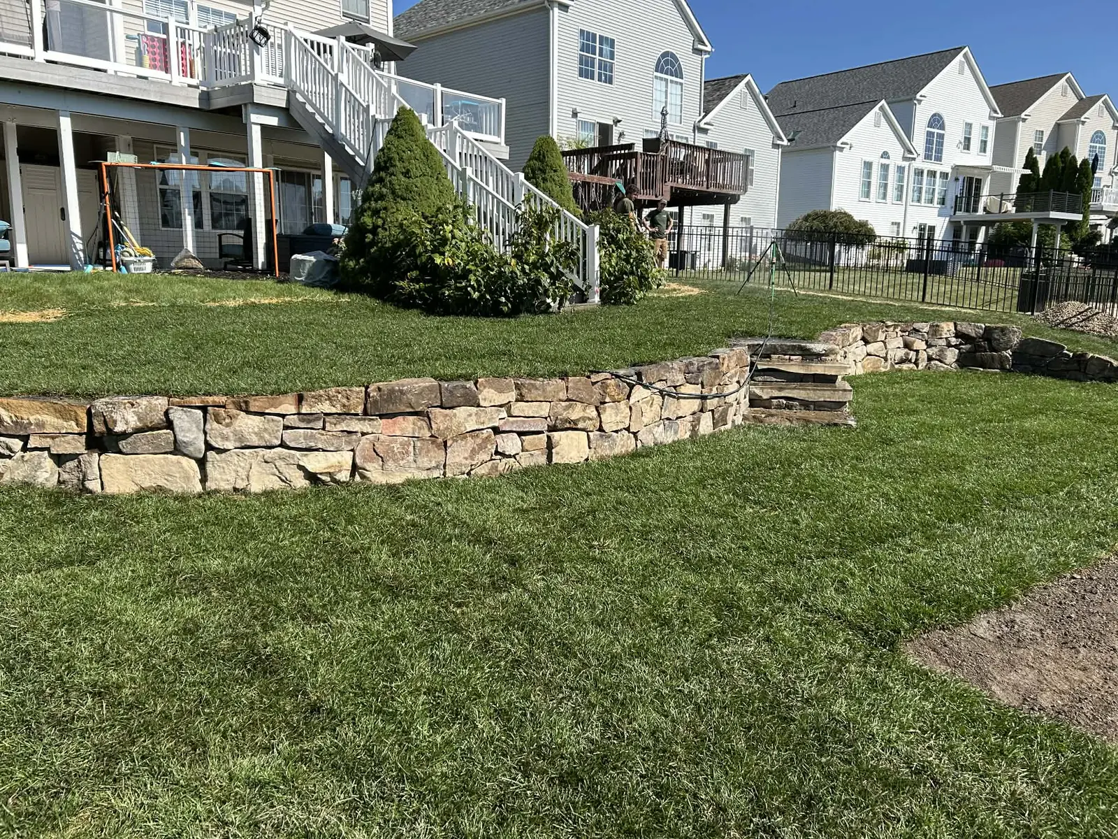 Natural stone retaining wall with landscaped lawn and steps
