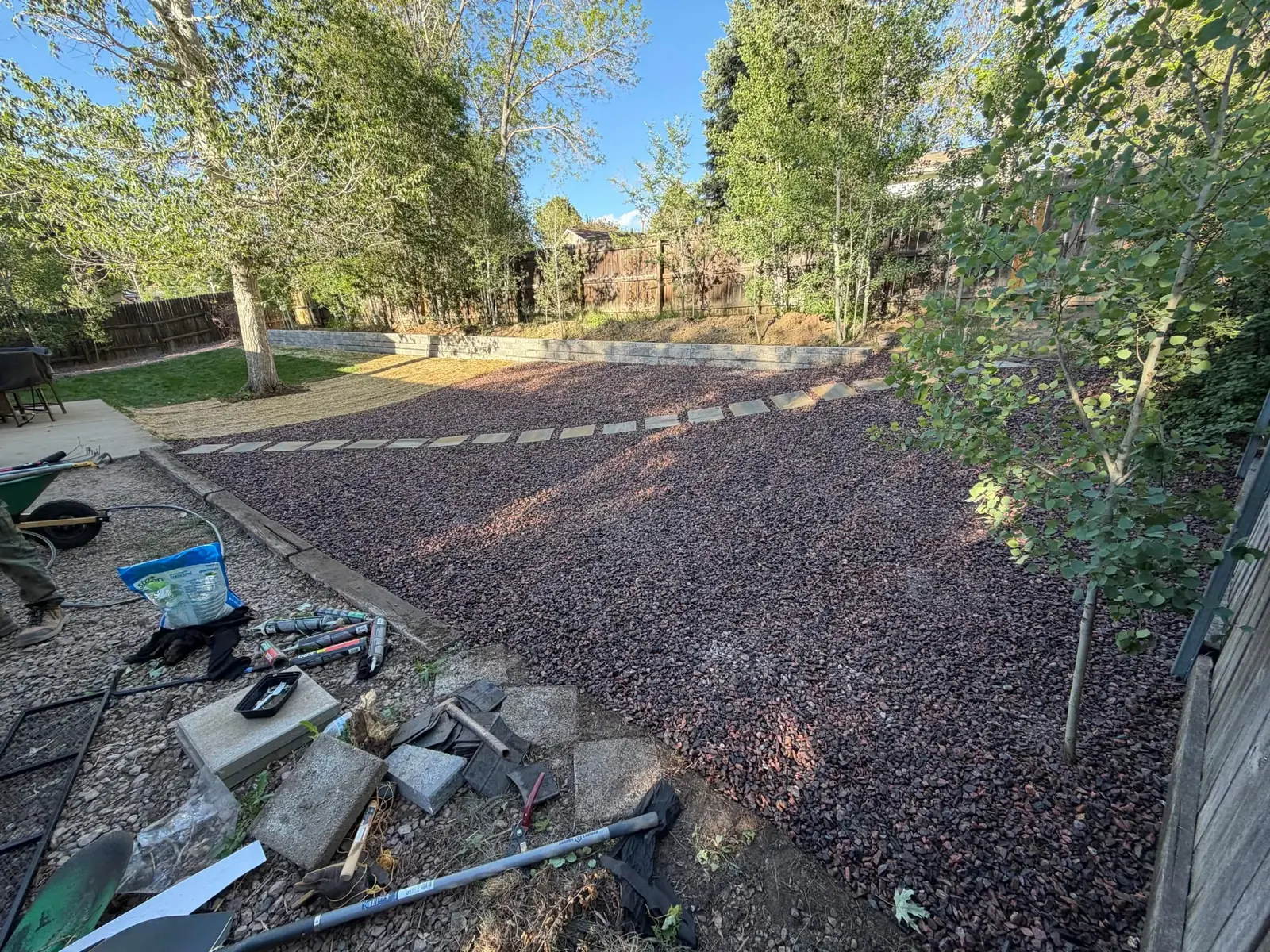 Wide view of decorative rock landscaping with retaining wall and trees